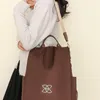Brauner Stoffrucksack mit oberen Griffen und einem Schultergurt, getragen von einer Person in einem hellgrauen Pullover Anteprima dell’immagine prodotto