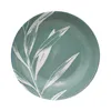 A top-down view of a round plate with a teal background and a white leaf pattern. Anteprima dell’immagine prodotto