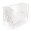 A white wooden baby crib with a teddy bear motif on the side panel, shown on a white background. Podgląd zdjęcia produktu