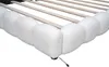 A close-up view of the corner of a white upholstered bed frame with wooden slats visible. Náhľad obrázku produktu