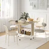 A dining set in a bright, modern room with a window and decorative wall art. Produktbild-Vorschau