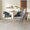 Two gray velvet dining chairs with gold metal legs are placed in a dining room setting. Produktbild-Vorschau