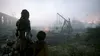 Two characters stand looking at a desolate, misty landscape with a trebuchet and fires in the background. Produktbild-Vorschau