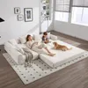A woman reads a book on a modular sofa while a child plays nearby and a dog rests on the floor. Anteprima dell’immagine prodotto
