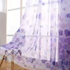 A sheer curtain with a heart pattern hangs in front of a window, partially covering a chair. Náhled obrázku produktu