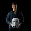 A young person holding a stormtrooper helmet in front of a black background. Voir les images du produit