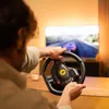 A person playing a racing video game using a steering wheel. Produktbild-Vorschau