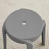 A close-up view of the top of a gray stool, showing the circular seat with a central hole and part of its legs. Voir les images du produit