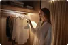 A woman is steaming a white shirt in a closet. Produktbild-Vorschau