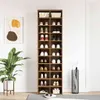 A tall, narrow shoe cabinet with multiple shelves filled with shoes and some decorative items, placed against a white wall next to a potted plant and an umbrella stand. Anteprima dell’immagine prodotto