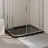 A close-up view of a black rectangular shower tray with chrome trim, set against a tiled wall and floor, with a bath mat and laundry basket visible. Produktbild-Vorschau