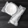A white mortar and pestle wrapped in bubble wrap, laid on a dark wooden surface. Produktbild-Vorschau