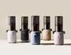Five juicers in different pastel colors are lined up against a light gray background. Produktbild-Vorschau