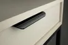 A close-up shot of a black drawer handle on a white drawer. Produktbild-Vorschau