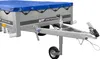 A close-up, angled view of a utility trailer with a blue tarp cover. Podgląd zdjęcia produktu
