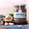 A jar of pickled cabbage with mushrooms, presented with garlic and bay leaves on a checkered cloth. Produktbild-Vorschau