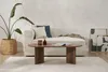 A living room scene featuring a couch, coffee table, plant, and artwork. Produktbild-Vorschau