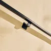A black metal handrail is mounted on a beige wall, casting a shadow. Podgląd zdjęcia produktu