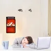 A woman is sleeping at her desk with a laptop and a mug, while a small electric heater with a flame effect is mounted on the wall. Anteprima dell’immagine prodotto