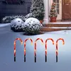 Candy canes are placed in the snow in front of a house with a snowy background. Náhľad obrázku produktu