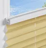 A close-up view of a beige pleated blind installed on a window frame, with a view of the sky and trees outside. Produktbild-Vorschau