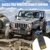 A silver Jeep Wrangler is shown off-road on rocky terrain, with a winch mounted on the front. A wireless remote control for the winch is shown in the foreground. Náhled obrázku produktu
