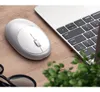 A white wireless mouse is placed on a wooden desk next to a laptop keyboard. Produktbild-Vorschau