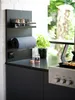 A kitchen counter with a magnetic paper towel holder, spice rack, and a plant. Anteprima dell’immagine prodotto