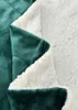 A close-up view of a folded green and white sherpa blanket. Produktbild-Vorschau