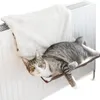 A cat is resting on a hammock attached to a radiator. Anteprima dell’immagine prodotto