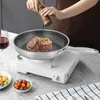 A person is seasoning steaks in a frying pan on a portable stove, with a glass of red wine and a bowl of cherry tomatoes nearby. Podgląd zdjęcia produktu