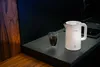 A white electric kettle and a glass of dark liquid on a dark countertop. Produktbild-Vorschau