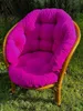 A bright pink cushion on a rattan chair in a garden setting. Produktbild-Vorschau