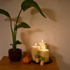 A set of three LED candles with a birch wood look, a small pumpkin decoration, and two mushroom figurines are arranged on a wooden surface next to a potted plant. Produktbild-Vorschau