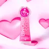 A lip balm and gloss product is displayed upright against a pink and white background with heart shapes. Anteprima dell’immagine prodotto