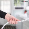 A hand is holding a white hose with red stripes, likely a washing machine inlet hose, in a blurred indoor setting. Náhled obrázku produktu
