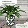 A plant in a decorative pot against a brick wall and wooden floor. Produktbild-Vorschau