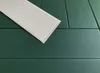 A close-up, angled view of dark green wall panels with a single white panel placed diagonally on top. Podgląd zdjęcia produktu