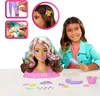 A young girl is shown smiling and holding a comb, with a Barbie styling head and accessories laid out on a table in front of her. Inset images show close-ups of hair clips being applied. Produktbild-Vorschau