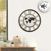 A wall clock with a world map design is displayed on a white wall above a wooden cabinet. Voir les images du produit