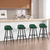 Four dark green bar stools are arranged in a row in front of a white fluted bar. A wooden shelf with various items is visible above the bar. Náhľad obrázku produktu