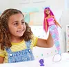 A young girl is playing with a Barbie mermaid doll and a small purple creature. Produktbild-Vorschau