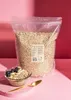 A large bag of oats is shown behind a bowl of oatmeal topped with blueberries and banana slices, with a golden spoon in the foreground. Produktbild-Vorschau