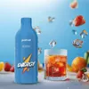 A bottle of energy drink and a glass of beverage with ice cubes and fruit scattered around. Produktbild-Vorschau