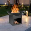 A black metal fire pit with a fire burning inside, set on a paved patio at dusk, with garden lights and greenery in the background. Voir les images du produit