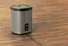 A silver and black speaker sits on a wooden floor. Anteprima dell’immagine prodotto