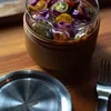 A glass lunch container filled with salad, placed on a wooden table next to its lid and a fork. Podgląd zdjęcia produktu