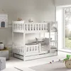 A white wooden bunk bed with a pull-out drawer, set up in a child's room with toys and a window view. Produktbild-Vorschau
