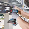 A person wearing protective gloves is using a Bosch cordless drill to fasten bolts on a metal structure. Produktbild-Vorschau