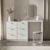 A white dresser with gold handles and a vanity table with a mirror and stool. Produktbild-Vorschau